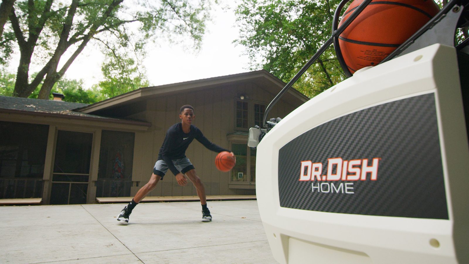 Young player dribbling in front of a Dr. Dish Home machine